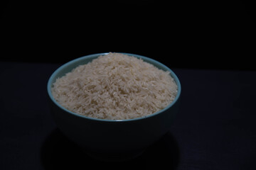 porcelain pan with raw white rice on black background