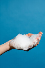 Closeup photo of hand with cleaning foam isolated over blue wall