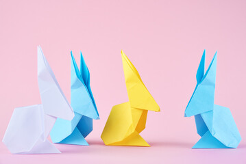 Paper colorful origami Esater rabbits on a pink background. Easter celebration concept