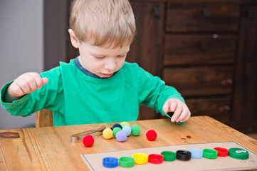 Naklejka premium Plastic bottle caps worm. Put correct color pom poms in centipede caterpillar. 5 minute carfts. DIY children home activity. Early education, fine motoric skills.