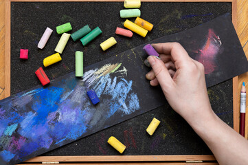 artist's hands with colored pastel crayons