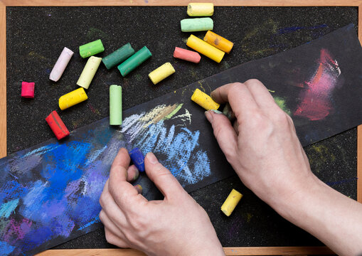 artist's hands with colored pastel crayons