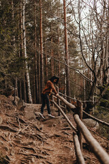 curly girl tourist stands on the path and holding onto a wooden fence in the forest in the Carpathian mountains in Ukraine