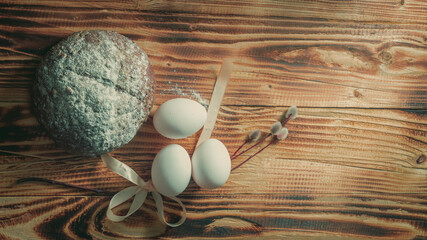 Easter composition in a simple style with white eggs, rye bread, a willow branch on a natural wooden background