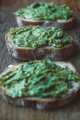 Slices of rye bread with avocado on a wooden background, simple rustic sandwich. Copy, empty space for text