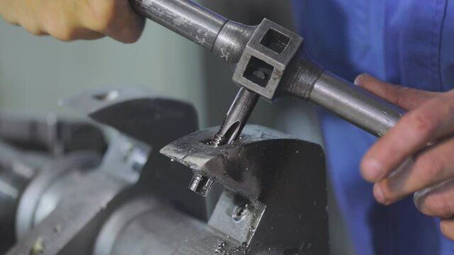 A man cuts a screw thread in a metal part. Working with a metal part. Screw thread cutting.