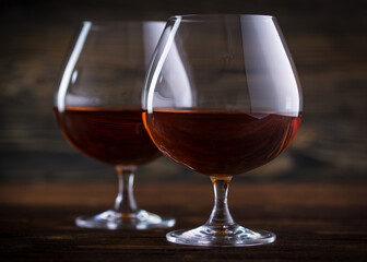 Two Glass of cognac, brandy or whiskey on natural wooden background. Classic cognac glass. Alcohol drink on Bar counter in the restaurant. 