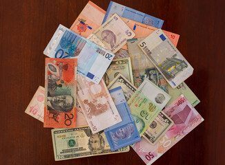 Multiple currencies from travels around the globe scattered on a wooden table