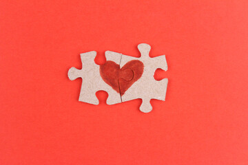 Red background with two halves of the heart on the pieces of the puzzle. The concept of relationship, togetherness, love
