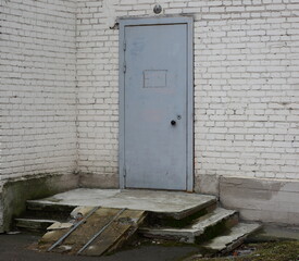 A gray metal front door set in a white brick wall