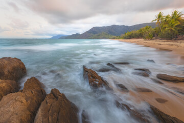 Rocky shoreline on an idyllic, tropical sandy Thala Beach near Oak Beach at sunrise or sunset outside Port Douglas and the Daintree in Queensland, Australia.