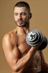 Fototapeta na wymiar Strong adult athlete man with powerful torso posing with special tool at the photo camera in studio