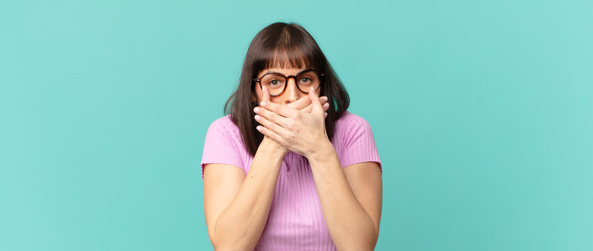 pretty woman covering mouth with hands with a shocked, surprised expression, keeping a secret or saying oops