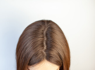 A woman's head with a parting of gray hair that has grown roots due to quarantine. Brown hair on a...