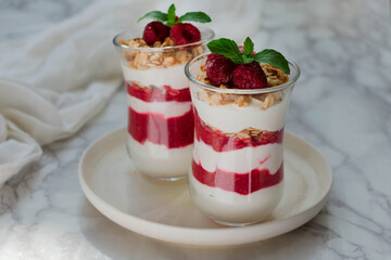 Cheesecake in a glass with fresh raspberries and cream cheese on a marble table. Healthy homemade organic dessert.	