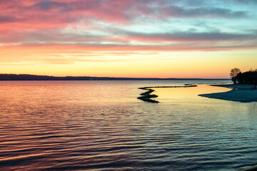 Beautiful sunset over the sea on a frosty weather. Colorful sky with clouds reflected in the water.