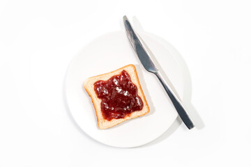 Slice of toasted bread with red strawberry jam in a white plate isolated on white background - top view