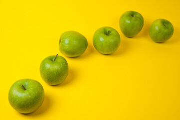 Large green apples, ripe and juicy. Photographed against a uniform yellow background.