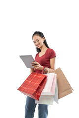 Beautiful woman holding a shopping bag and looking the tablet with smile expression on white background