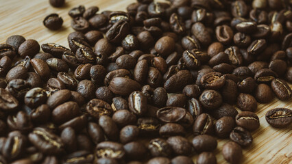 Freshly roasted aromatic coffee beans for filter coffee makers are scattered on a wooden table