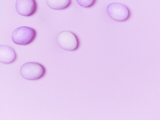 Creatively painted eggs in pastel colors on purple background. Copy space. Happy Easter concept. Flat lay.