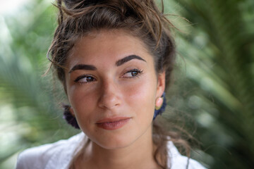 Portrait of young beautiful woman close up in white shirt  and palm trees view on background
