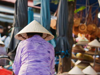 rear view of a woman on a market with traditional vietnamese clothes and Asian rice hat