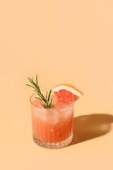 Grapefruit juice garnish rosemary sprig on color beige background. Mocktail Paloma. Close up. Vertical format.
