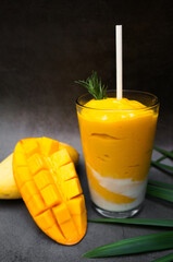 Mango smoothie in a glass Mason jar and mango on a dake background. Mango shake. Tropical fruit...