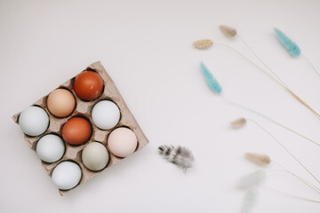 fresh chicken eggs of natural shades and colors in a recycled box on a white background