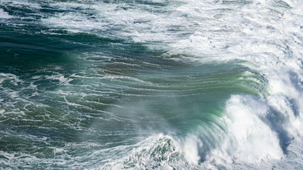 Fototapeta premium Giant turquoise ocean waves crash on the water surface forming a rainbow