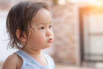 A toddler girl stood looking forward, looking forward to hope with a sweat wet state.