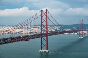 Modern bridge On April 25 in Lisbon, the capital of Portugal, in cloudy cloudy weather, cars drive on the gigantic bridge across the strait.