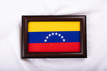 Venezuela flag in a realistic frame on white cloth background flat lay photo