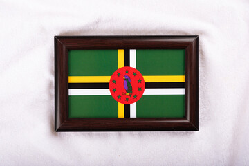 Dominica flag in a realistic frame on white cloth background flat lay photo