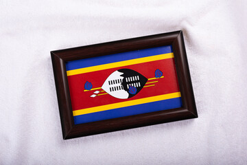 Eswatini formerly Swaziland flag in a realistic frame on white cloth background flat lay photo