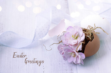 Easter greetings - text. small pink flowers in an egg shell, ribbon. 