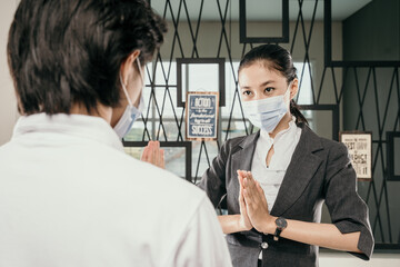 women greeting man guest using health mask to protect and keep social distance, new greeting practice in coronavirus covid 19 pandemic