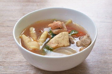 spicy chicken meat and foot in tom yum soup on bowl