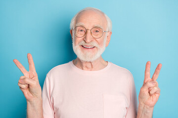 Photo of aged man happy positive smile show fingers peace cool v-sign isolated over blue color...