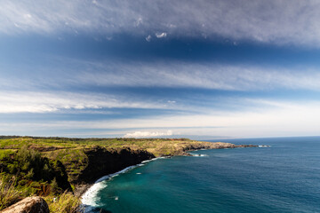 Fototapeta na wymiar Long stretches of clouds in the tropical sky reach to the horizon over the Pacific Ocean along the Honoapiilani Highway in northwestern Maui, Hawaii 