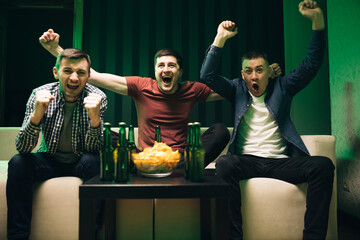 Cheerful happy Caucasian guys cheering for favorite team. Loyal football fans supporting their...