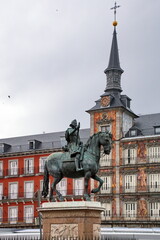 Fototapeta na wymiar Bronze statue of King Philip III at the center of Plaza Mayor, a major public space in the heart of Madrid, Casa de la Panaderia (Bakery House) on background.