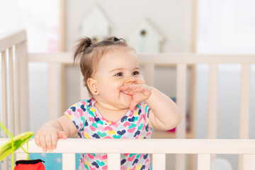 happy baby laughing at home in the nursery, portrait of baby in the crib