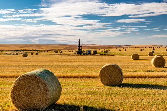 Oil derreck in a hay field surrounded by hay bales. Kneehill County, Alberta, Canada