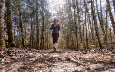 Caucasian Woman Trail Running in the Green Forest surrounded by beautiful trees. Taken in Squamish, British Columbia, Canada.