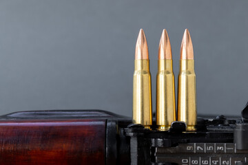 Three bullets on Kalashnikov assault rifle against blurred gray background. Cartridges 7.62 caliber...