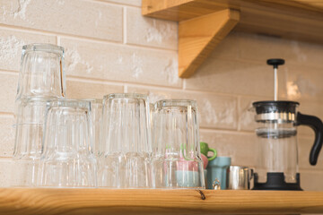 Wooden shelf on the wall with glasses, a jar, and a teapot