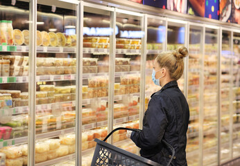 supermarket shopping, face mask and gloves,Woman choosing frozen food from a supermarket freezer