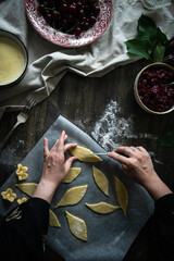 Fototapeta na wymiar Step by step process of making cherry custard pie. Woman making dough leaves and flowers to decorate a pie.